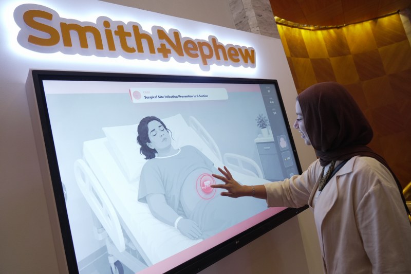 Attendee using interactive touchscreen display on Surgical Site Infection Prevention at the Smith+Nephew Academy conference